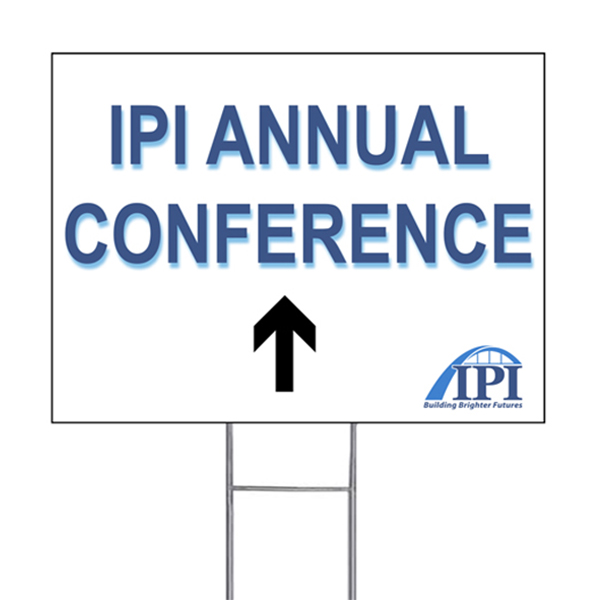 White corrugated wayfinding sign pointing towards IPI Annual Conference.